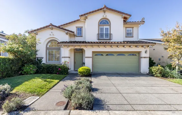 a view of a white house with potted plants and a large tree