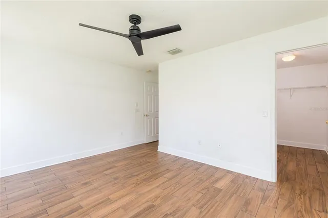 a view of a room with wooden floor and a ceiling fan