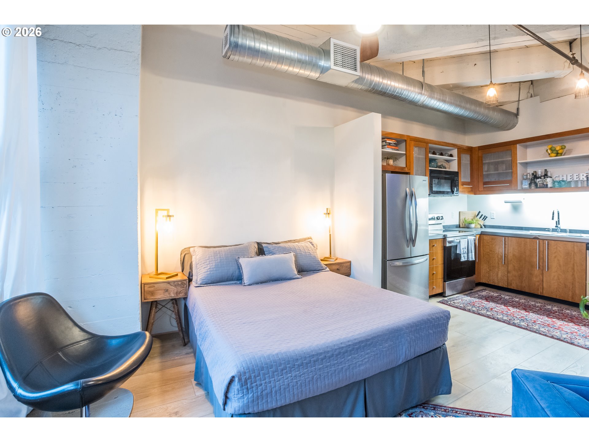 1420 Northwest Lovejoy Street, Unit 417 Portland, OR 97209 - Photo 19 of 40 a bedroom with a bed a mirror and lamp