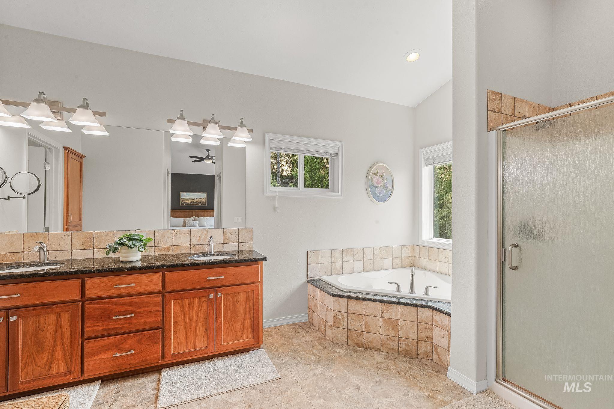 602 Quarry Road Asotin, WA 99402 - Photo 25 of 49 Spacious bathroom featuring a dual vanity with wood-finish cabinetry, a large soaking tub with tiled surround, a separate glass-enclosed shower, and windows providing natural light