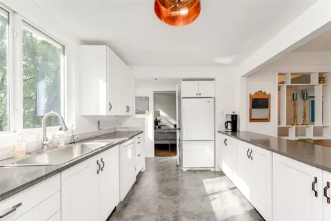 a large white kitchen with granite countertop a sink and appliances