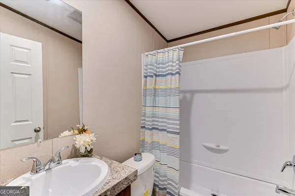 a bathroom with a granite countertop sink a toilet and shower