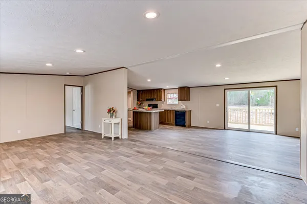 a view of an empty room with kitchen counter and a refrigerator
