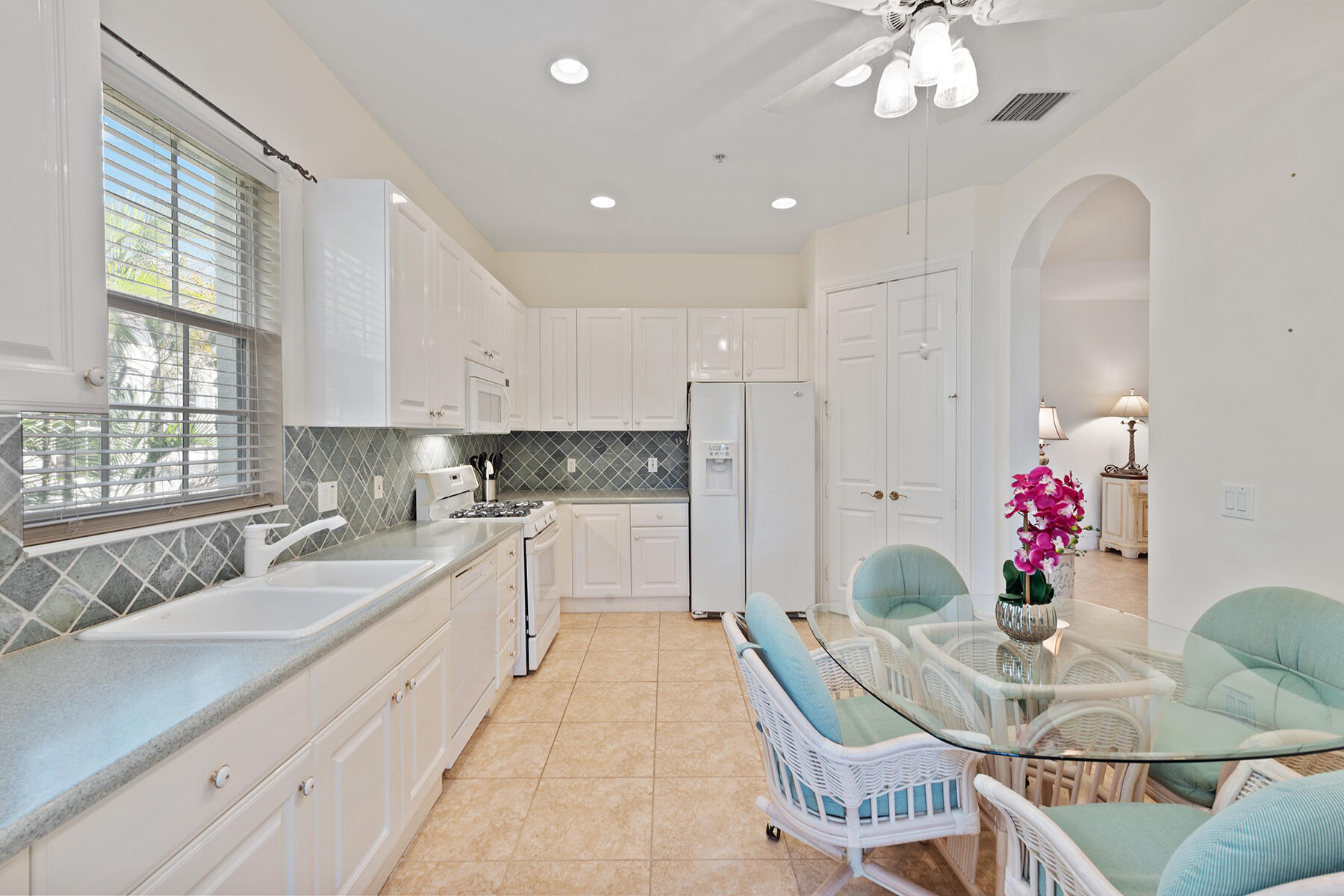 9082 Cascada Way, Unit 202 Naples, FL 34114 - Photo 4 of 37 a kitchen with stainless steel appliances kitchen island granite countertop a sink dishwasher a dining table and chairs with wooden floor