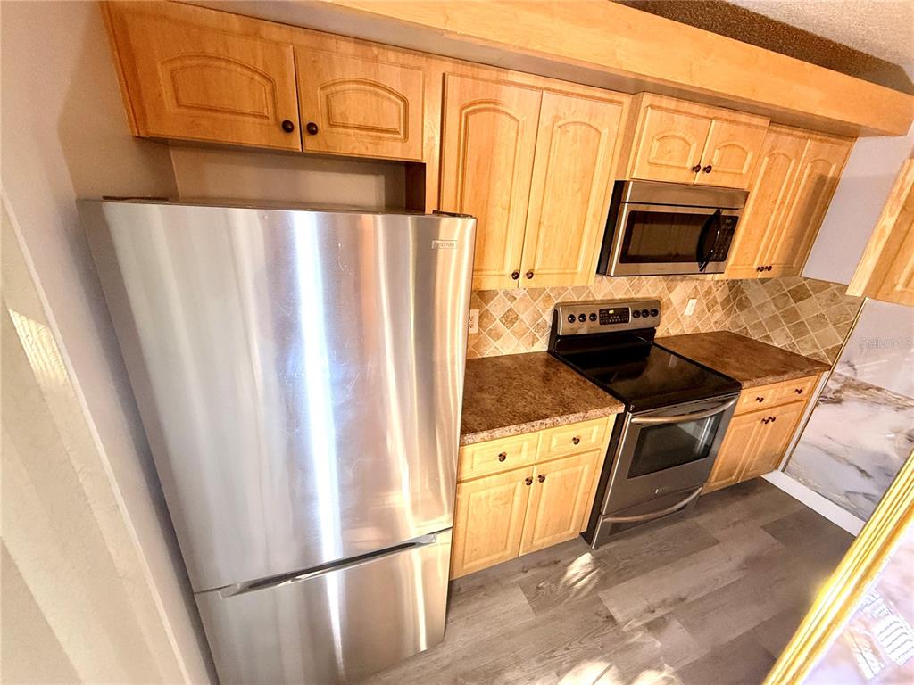 2727 14th Court Palm Harbor, FL 34684 - Photo 12 of 42 a kitchen with stainless steel appliances a refrigerator a stove a microwave oven cabinets and a sink
