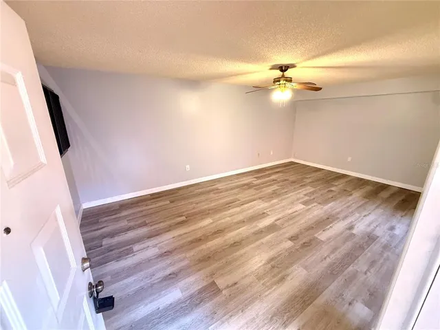 a view of a room with wooden floor and a ceiling fan