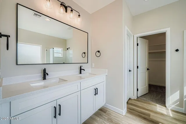 a en suite bathroom with a double vanity sink and a mirror