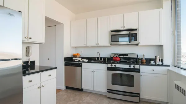 a kitchen with granite countertop white cabinets and stainless steel appliances