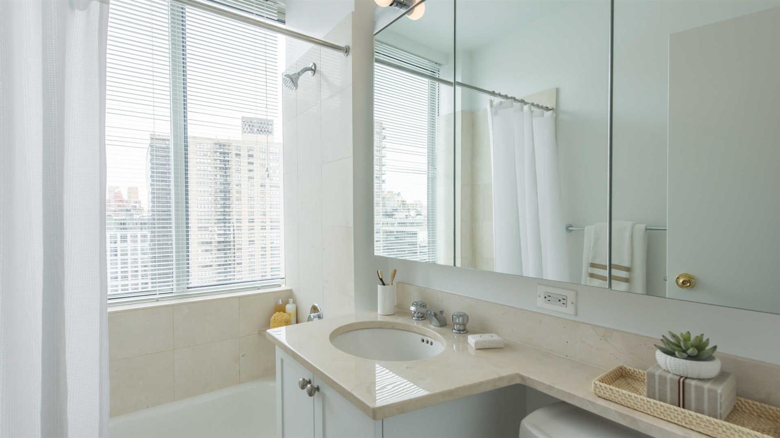 180 Riverside Boulevard, Unit 9M Manhattan, NY 10069 - Photo 7 of 10 a bathroom with 2 sink tub and a mirror