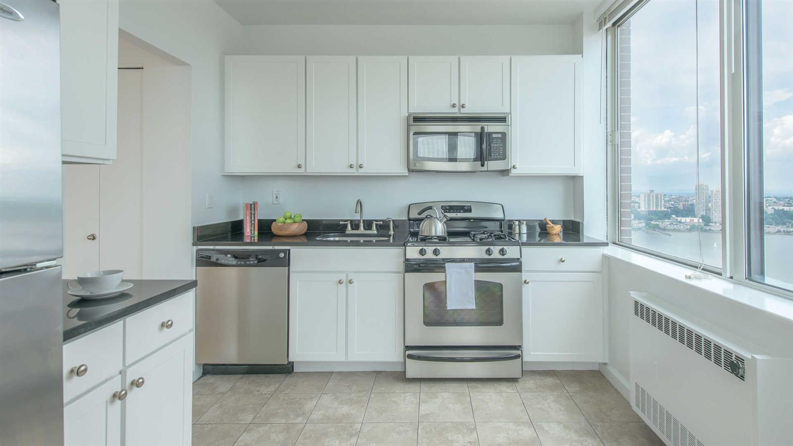 180 Riverside Boulevard, Unit 9M Manhattan, NY 10069 - Photo 8 of 10 a kitchen with white cabinets and white appliances