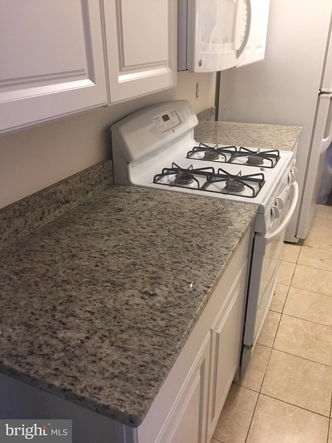 12700 Epping Terrace, Unit 8D Silver Spring, MD 20906 - Photo 3 of 6 a kitchen with granite countertop a sink stove and cabinets