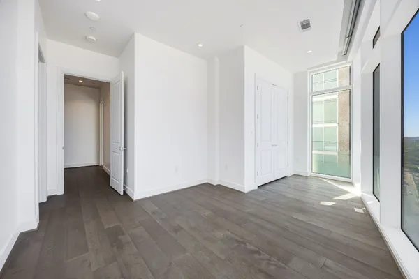 an empty room with wooden floor & windows