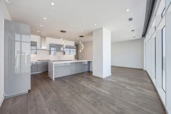 a view of kitchen with stainless steel appliances refrigerator oven a sink dishwasher and white cabinets with wooden floor