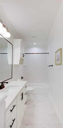 a bathroom with a double vanity sink a toilet and a bathtub