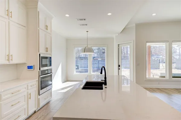 a kitchen with stainless steel appliances a microwave a stove and white cabinets with wooden floor