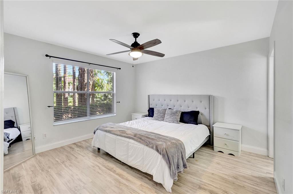 1965 Courtyard Way, Unit E106 Naples, FL 34112 - Photo 6 of 15 a bedroom with a large bed and a chandelier