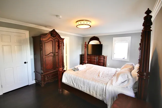 a bedroom with a bed and a dresser with wooden floor