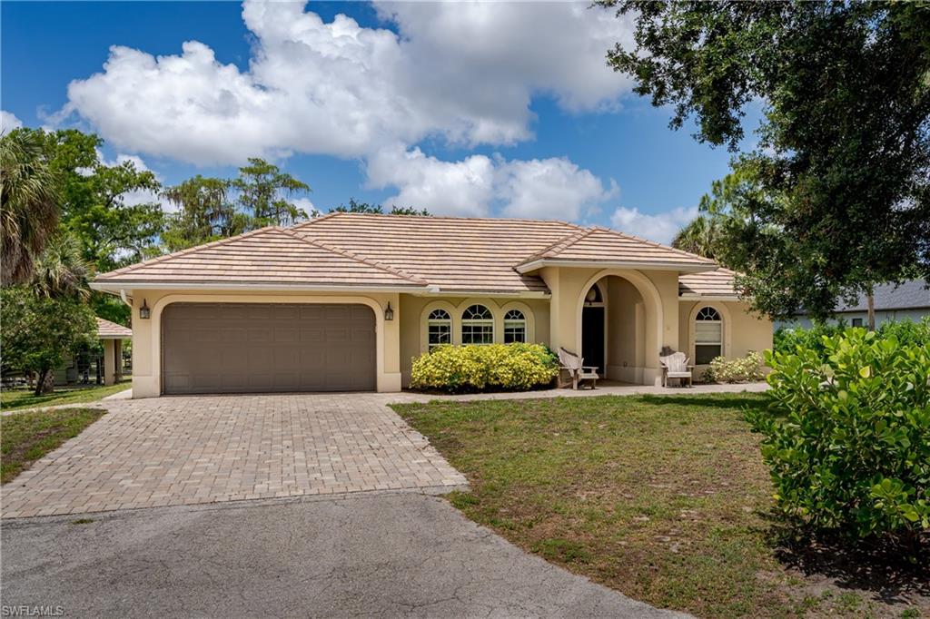 1781 21st Street Southwest Naples, FL 34117 - Photo 2 of 39 a front view of a house with a garden and yard
