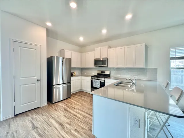 a kitchen with refrigerator a microwave a sink and cabinets