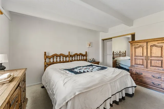 a bedroom with a bed and dresser with wooden floor