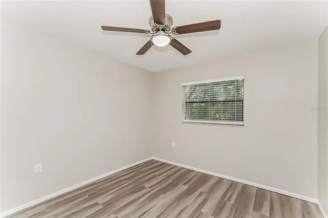 an empty room with a window and a fan