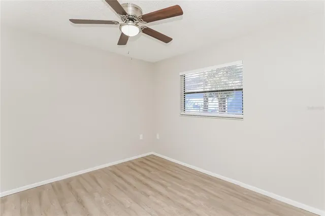 an empty room with a window and a ceiling fan