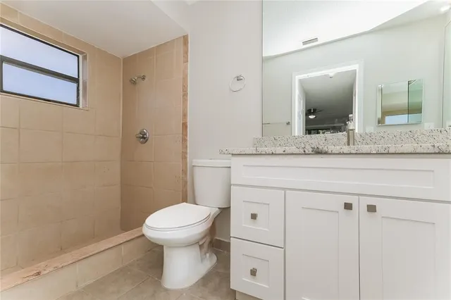a bathroom with a granite countertop sink toilet and mirror