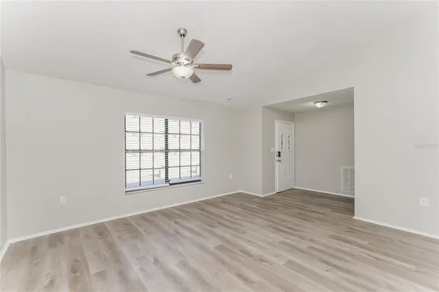 a view of empty room with wooden floor and fan