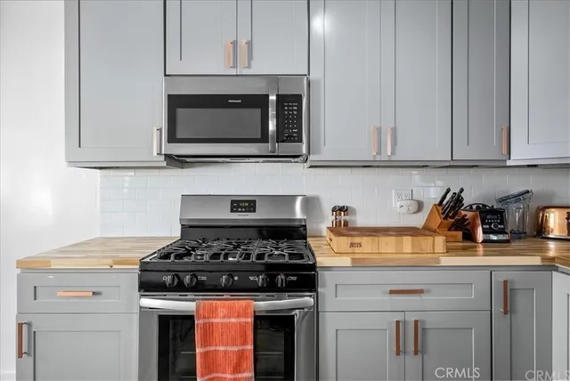 a kitchen with stainless steel appliances granite countertop white cabinets and a stove top oven