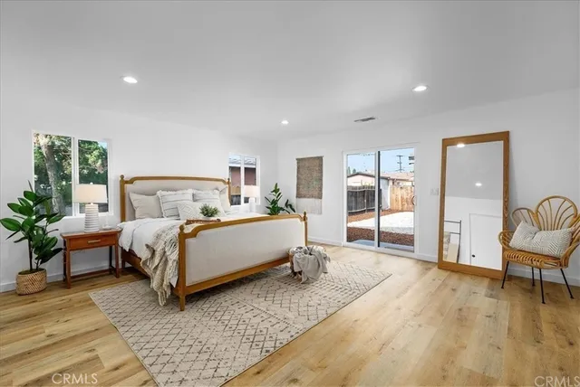 a bedroom with a bed wooden floor and windows