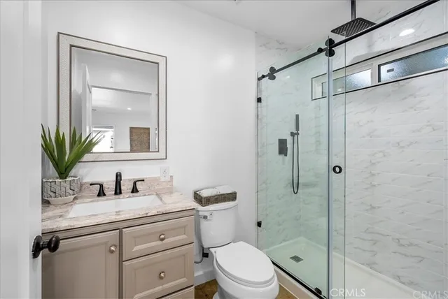 a bathroom with a shower sink vanity mirror and toilet