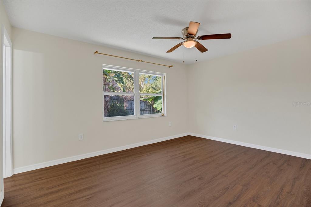 5357 Sunrise Boulevard Orlando, FL 32803 - Photo 11 of 26 an empty room with wooden floor ceiling fan and windows