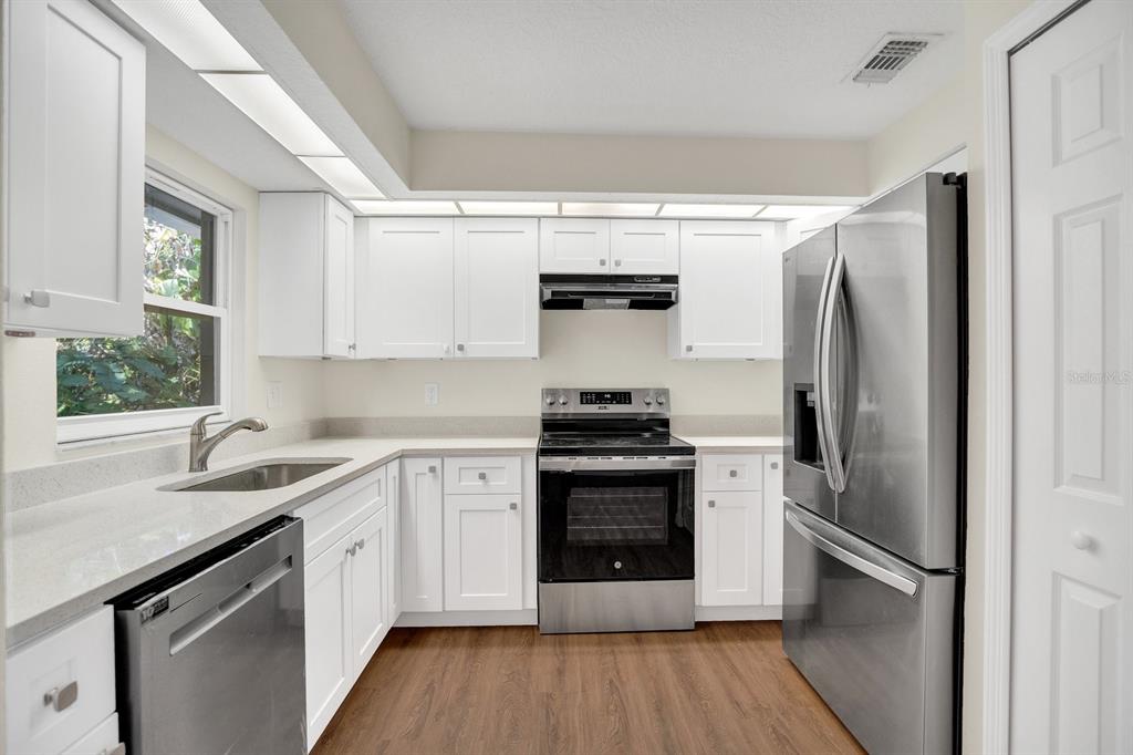 5357 Sunrise Boulevard Orlando, FL 32803 - Photo 4 of 26 a kitchen with stainless steel appliances a sink cabinets and a wooden floor