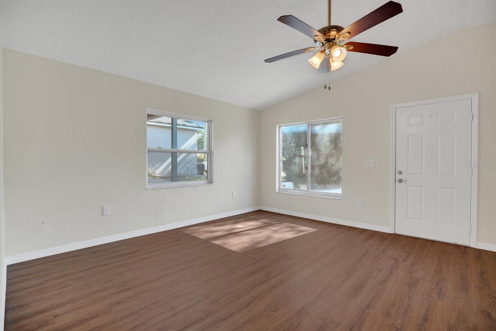 5357 Sunrise Boulevard Orlando, FL 32803 - Photo 9 of 26 an empty room with wooden floor chandelier fan and windows