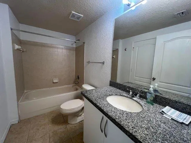 a bathroom with a granite countertop sink toilet and shower