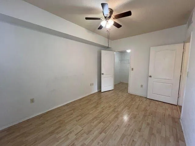 an empty room with wooden floor and ceiling fan