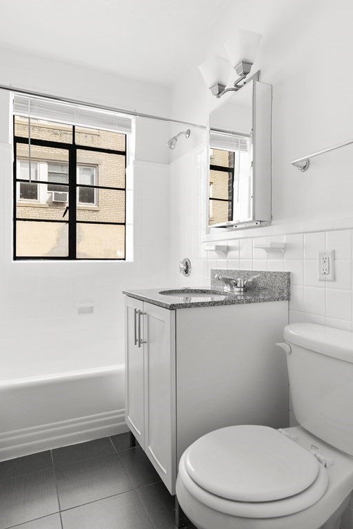 46 Chiswick Road, Unit 7 Boston, MA 02135 - Photo 9 of 16 a bathroom with a granite countertop toilet a sink and a bathtub