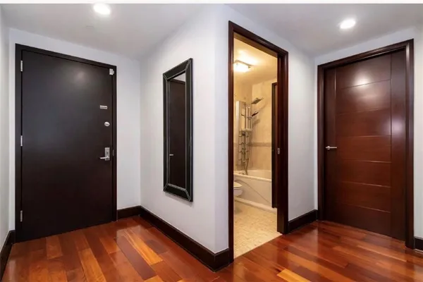 a view of an empty room with closet and wooden floor
