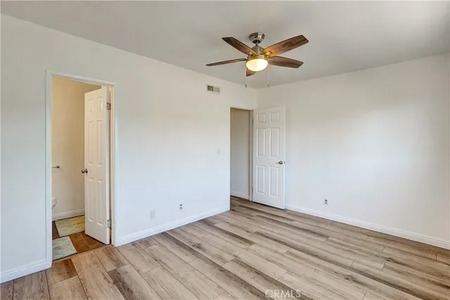 an empty room with wooden floor and a ceiling fan