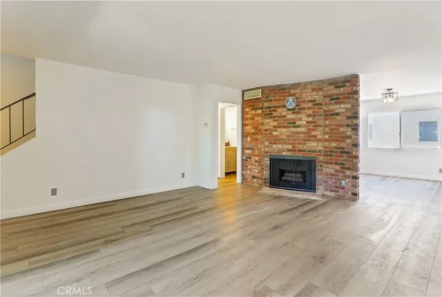 a view of an empty room with wooden floor fireplace and a window