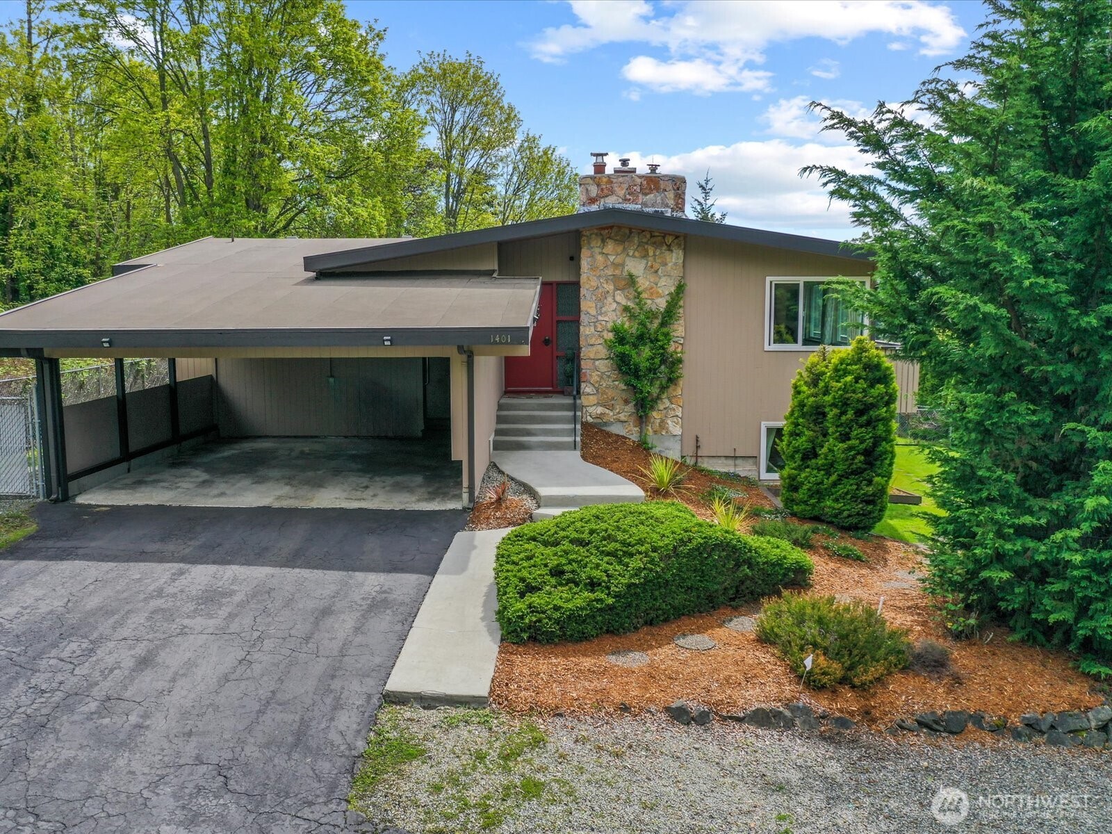 a view of a house with a yard plants and large tree