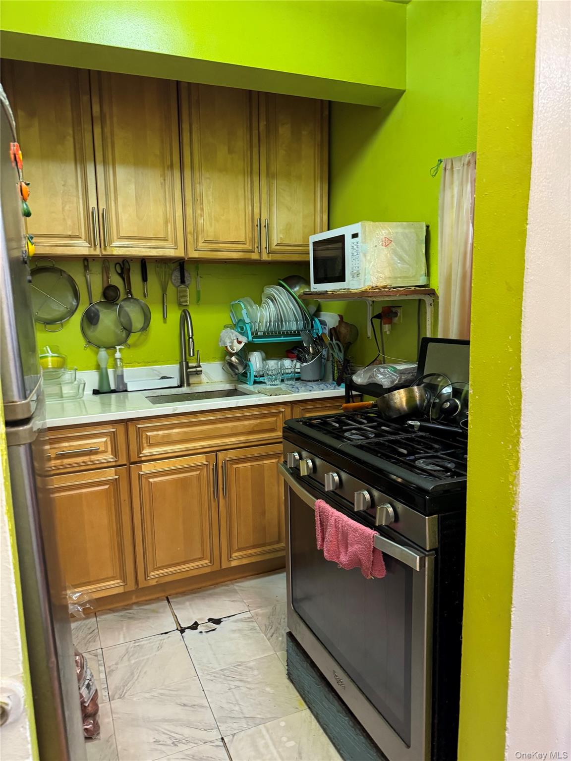 87-70 173rd Street, Unit 7H Queens, NY 11432 - Photo 4 of 6 Kitchen with appliances with stainless steel finishes, light countertops, light marble finish flooring, and brown cabinets