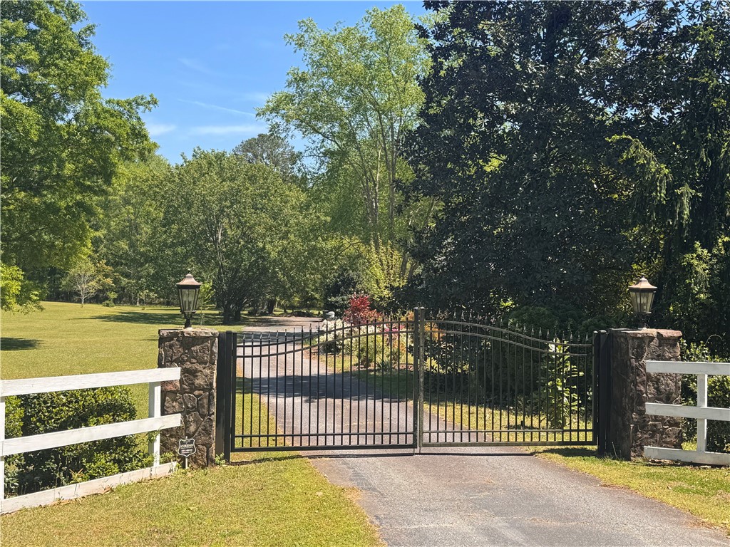 208 Knoxwood Court Anderson, SC 29621 - Photo 34 of 38 A private driveway leads to a gated entrance, surrounded by lush green landscaping and mature trees.