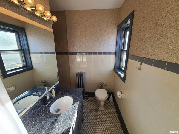 a bathroom with a granite countertop sink a toilet and a mirror