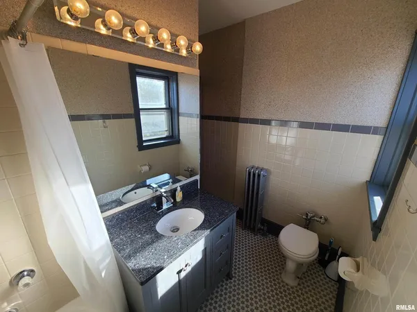 a bathroom with a granite countertop sink mirror vanity and toilet