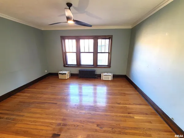 a view of empty room with wooden floor and fan