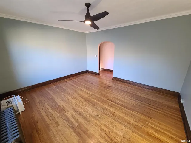 an empty room with wooden floor fan and windows