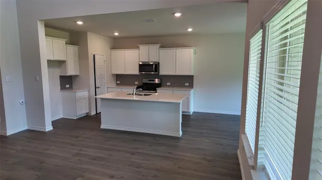 a view of kitchen with kitchen island stainless steel appliances refrigerator stove microwave and cabinets