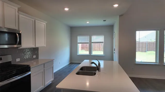 a kitchen with sink a microwave and cabinets