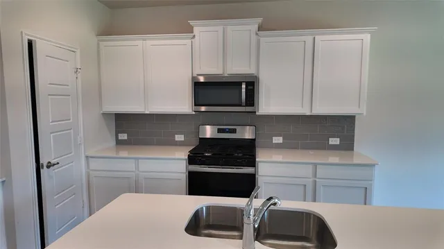 a kitchen with white cabinets and black appliances